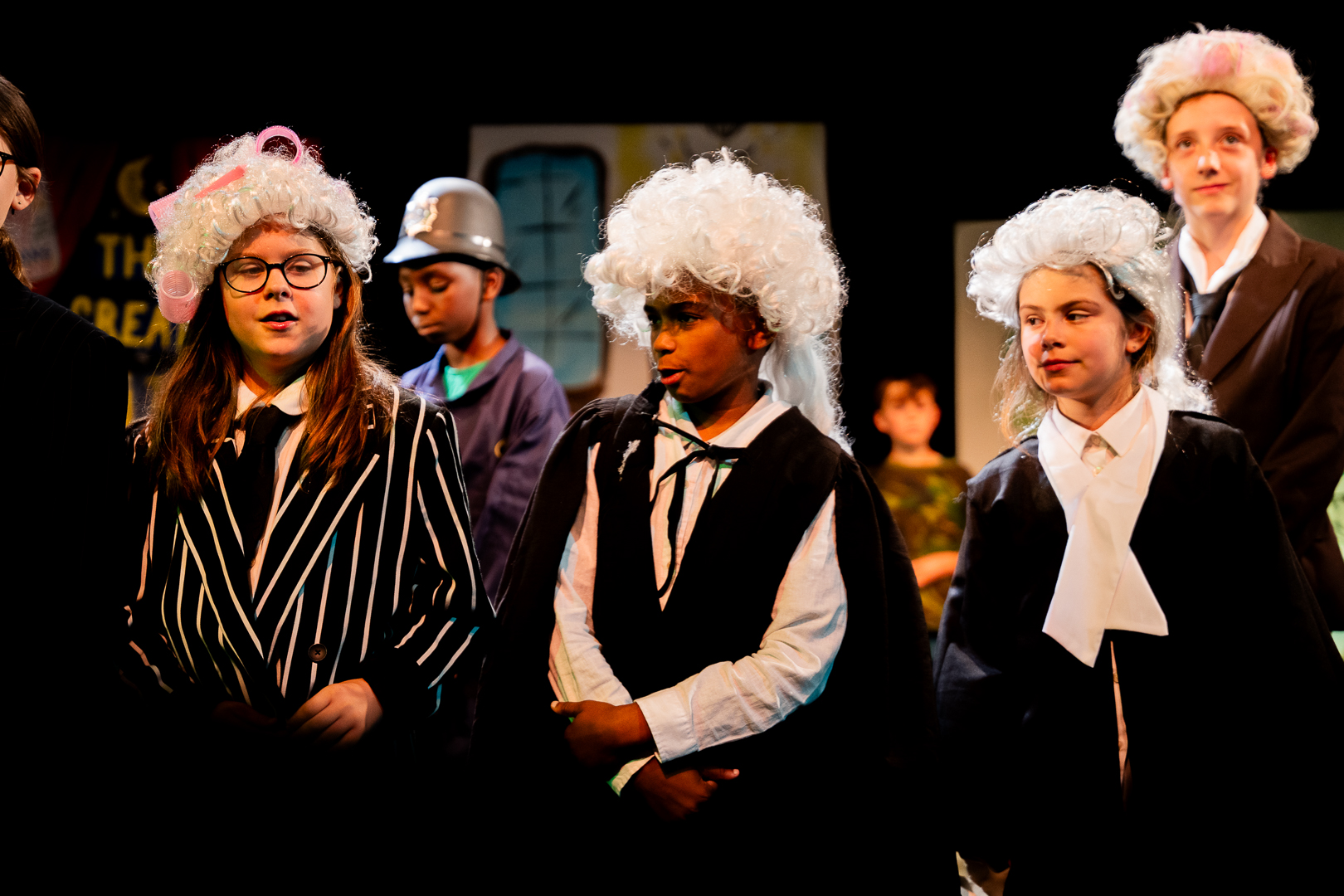 Group of children performing in a theatre with elaborate outfits