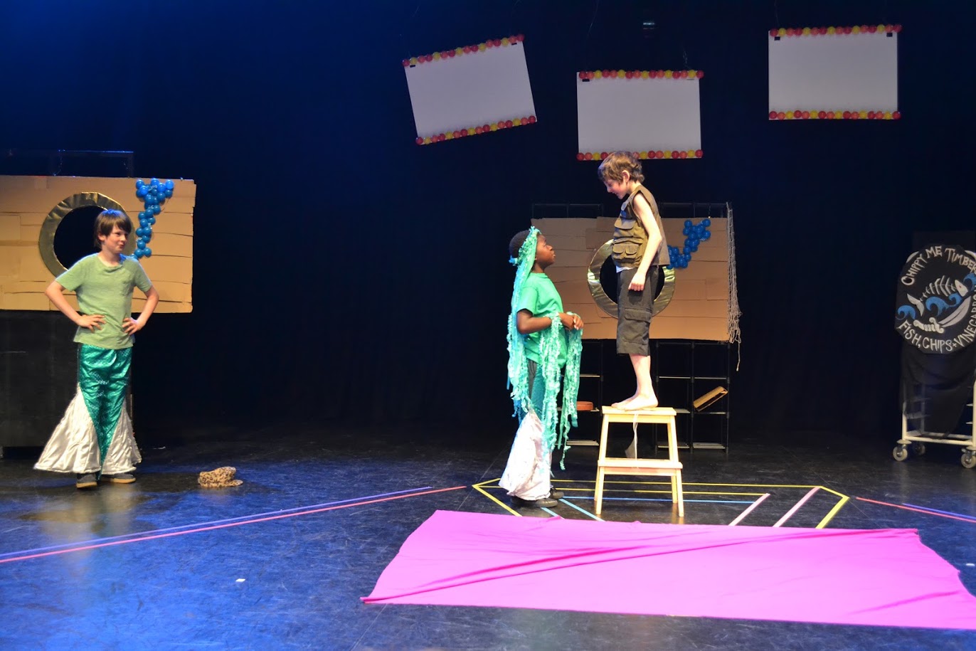 Group of children performing in a theatre with elaborate outfits