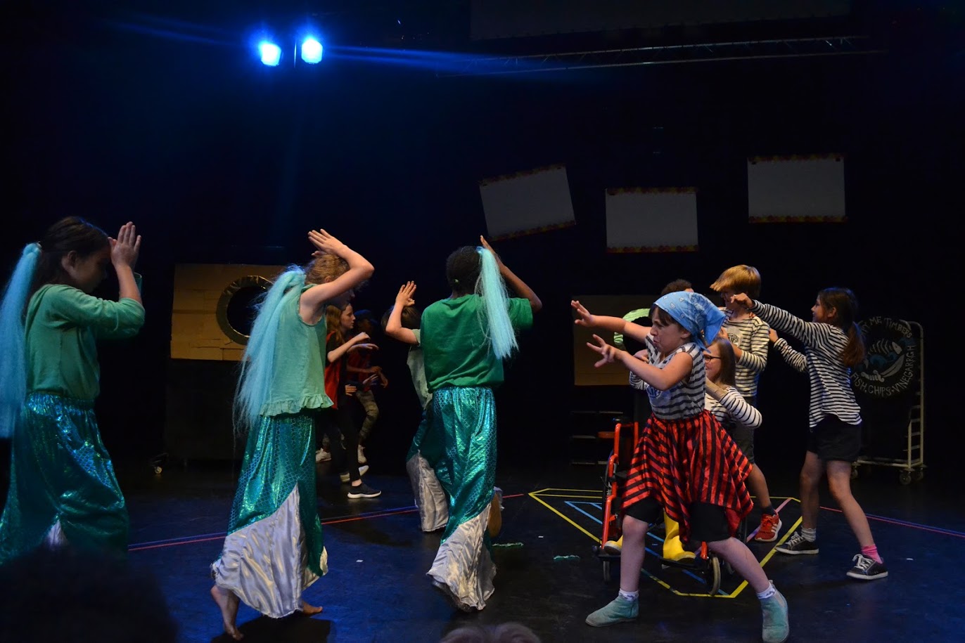 Group of children performing in a theatre with elaborate outfits