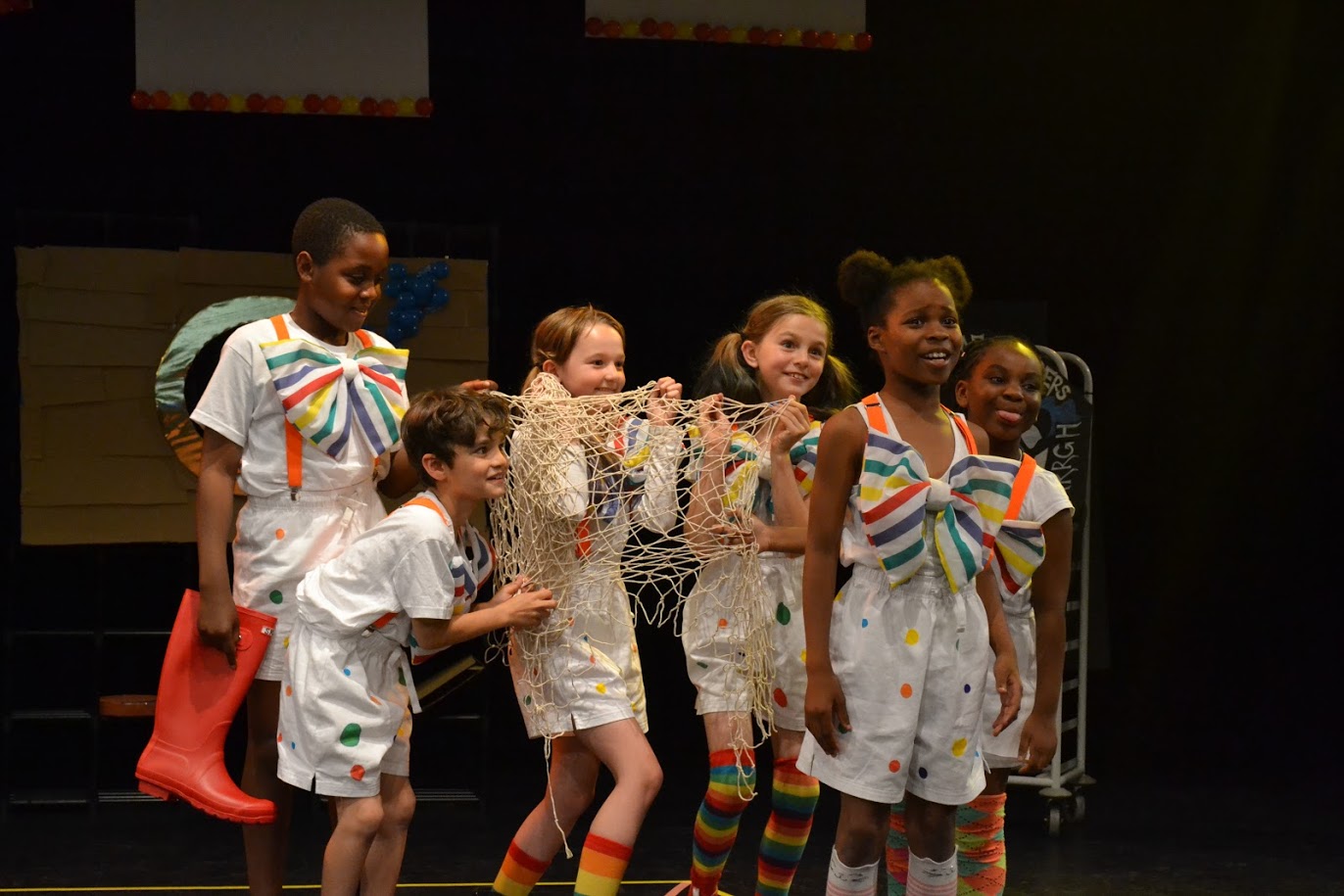 Group of children performing in a theatre with elaborate outfits