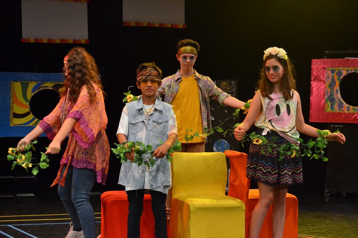 Young people in a theatre performance with colourful outfits