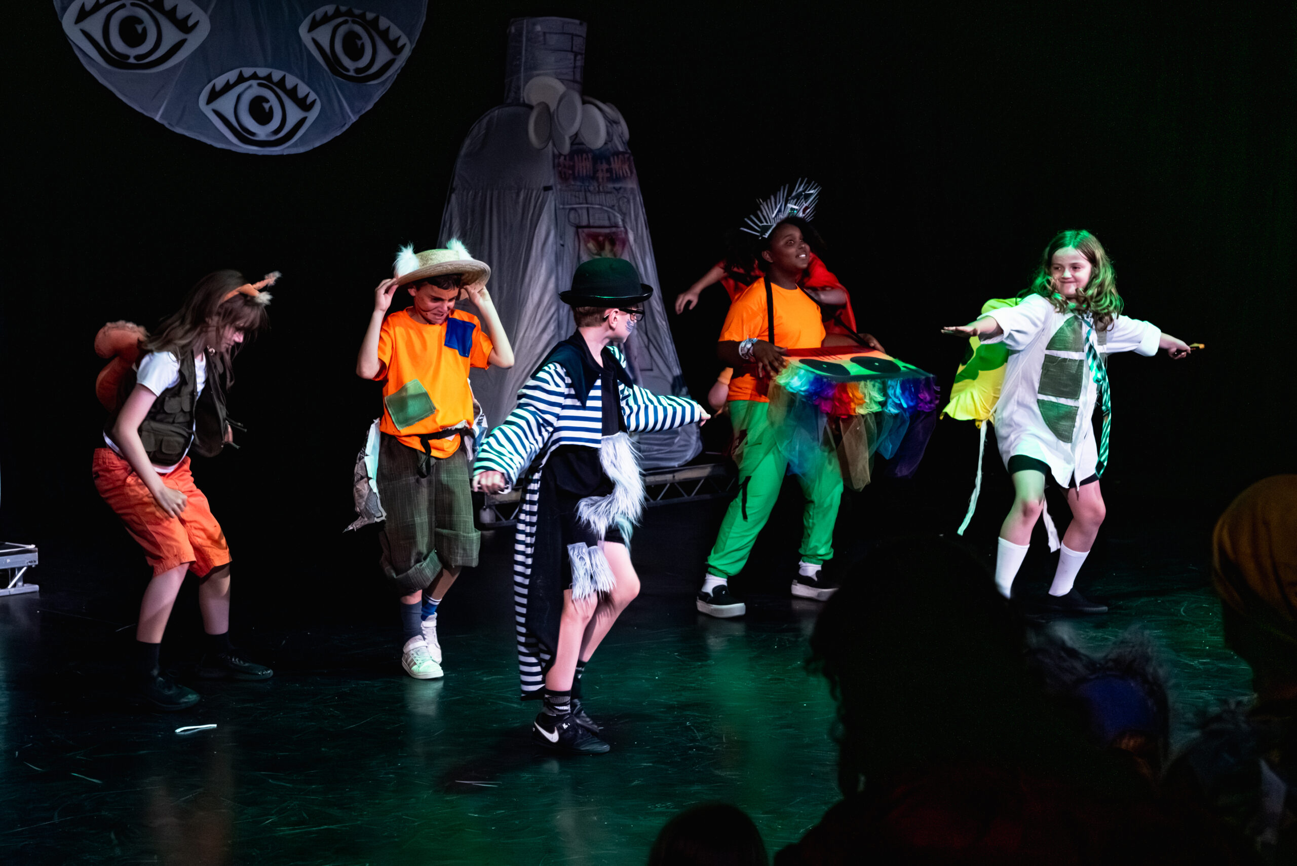 Group of children performing in a theatre with elaborate outfits