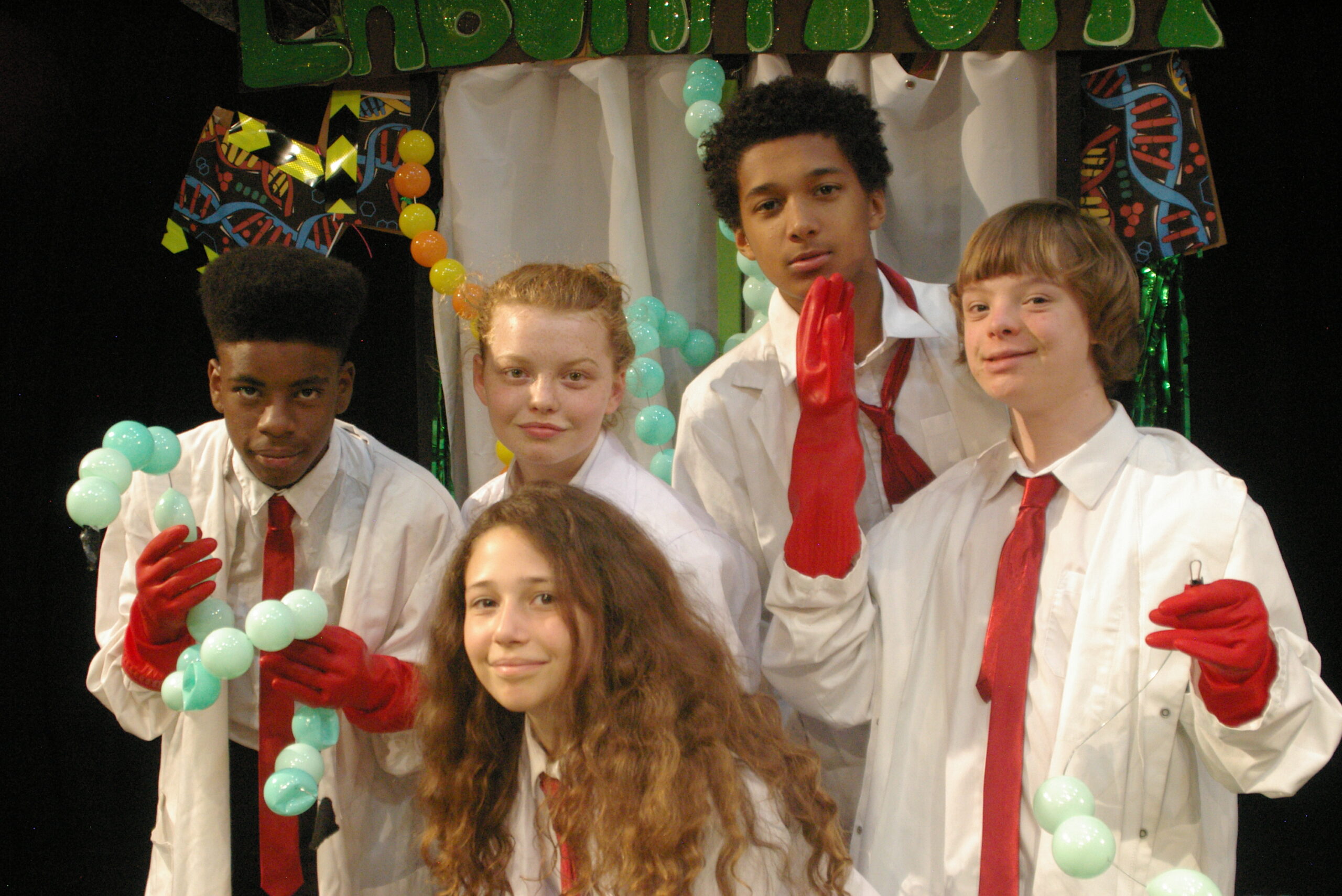 Group of children wearing white shirts and lab coats as part of a production project with Hackney Shed