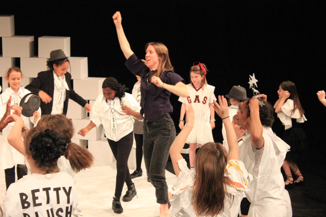 Large Group of Young people in a theatre performance with adult in the middle
